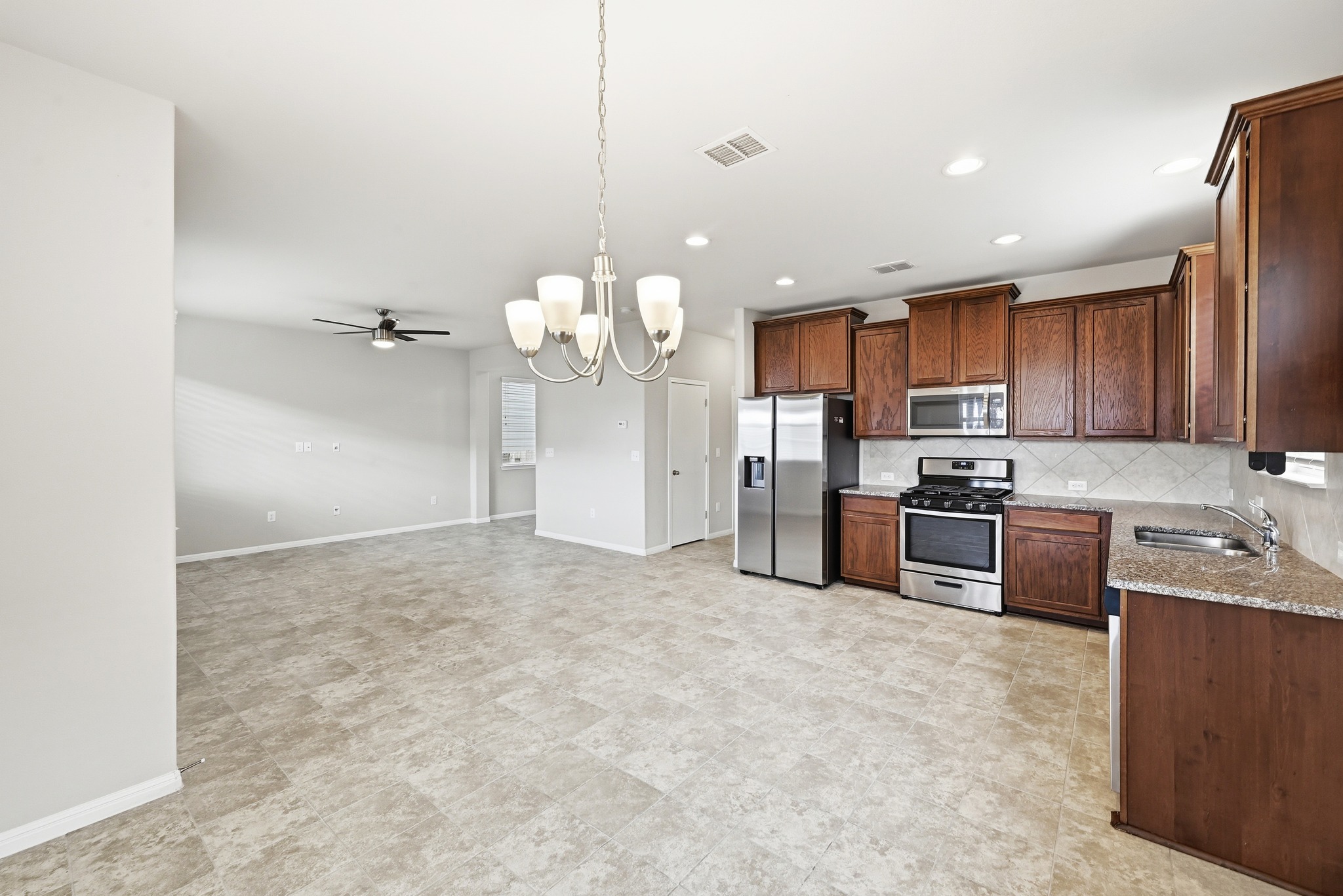 171 Vestral Road Buda, TX 78610 - Photo 10 of 26 Kitchen featuring a dining area with chandelier, stainless steel appliances, gas range and decorative backsplash