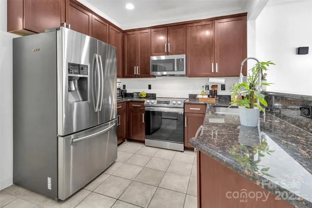 a kitchen with stainless steel appliances granite countertop a refrigerator a stove a sink a microwave and island