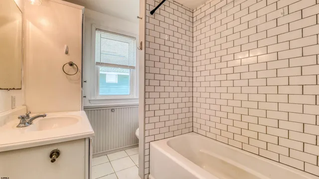 a bathroom with a sink a bathtub and next to a window