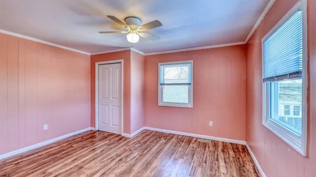 a view of an empty room with a window and wooden floor