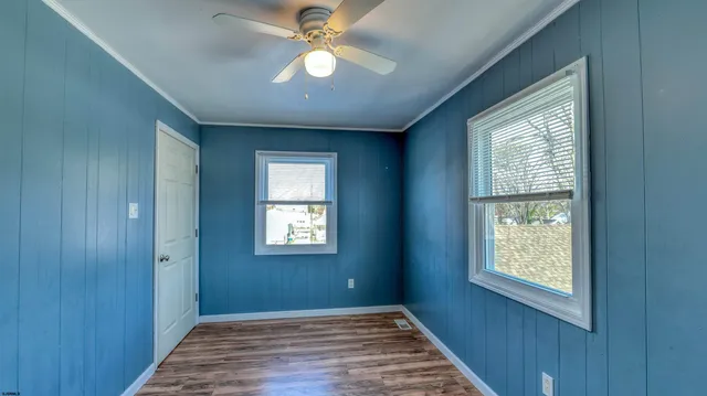 a view of an empty room with a window and wooden floor