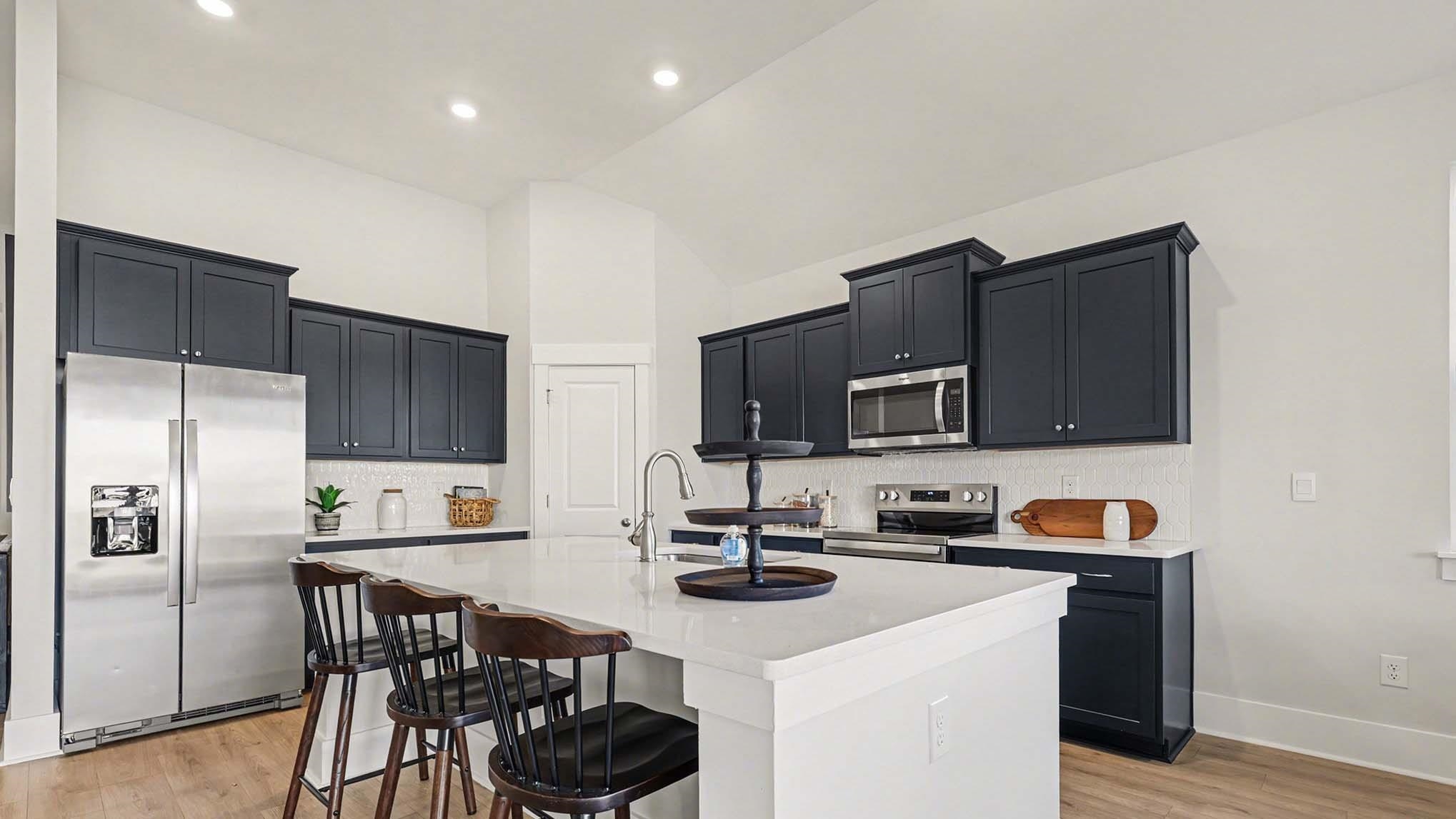 3250 Moss Bridge Lane Myrtle Beach, SC 29579 - Photo 10 of 29 Kitchen with dark cabinetry, appliances with stainless steel finishes, decorative backsplash, light wood-type flooring, and an island with sink