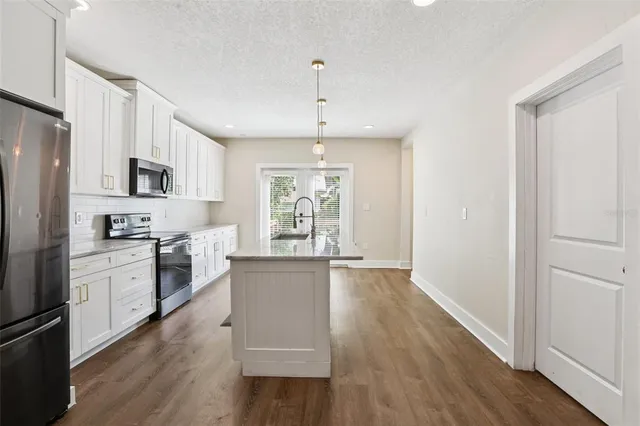 a kitchen with kitchen island granite countertop a sink a counter top space stainless steel appliances and cabinets