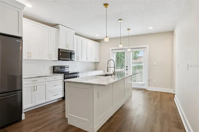 a kitchen with stainless steel appliances granite countertop a refrigerator a sink a stove a microwave and wooden floors