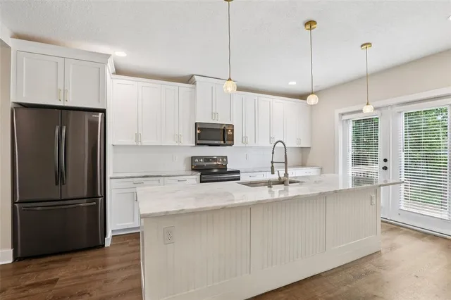 a kitchen with stainless steel appliances granite countertop a sink a stove top oven a counter space and cabinets