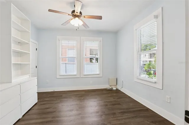 a view of an empty room with a window and wooden floor