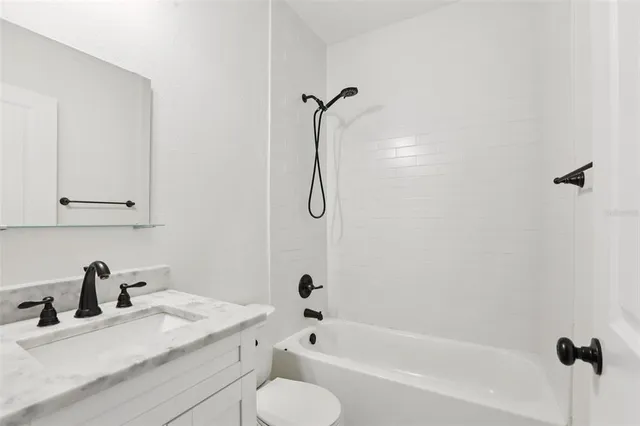 a bathroom with a granite countertop sink vanity mirror and bathtub