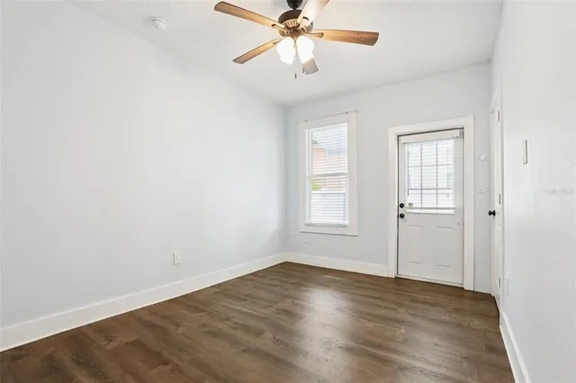 an empty room with wooden floor fan and windows