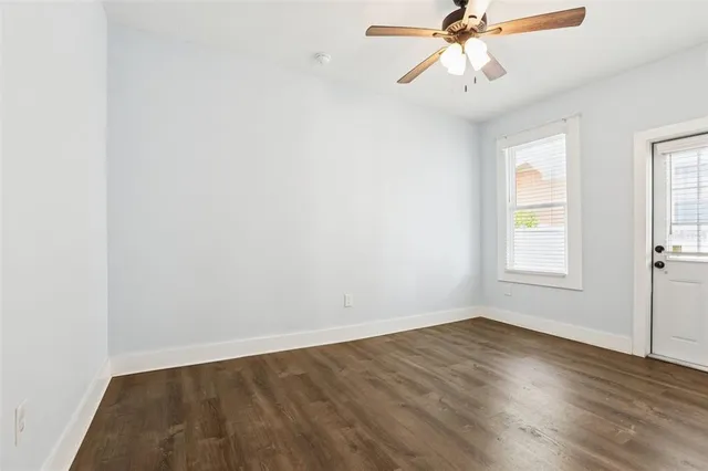 an empty room with wooden floor fan and windows