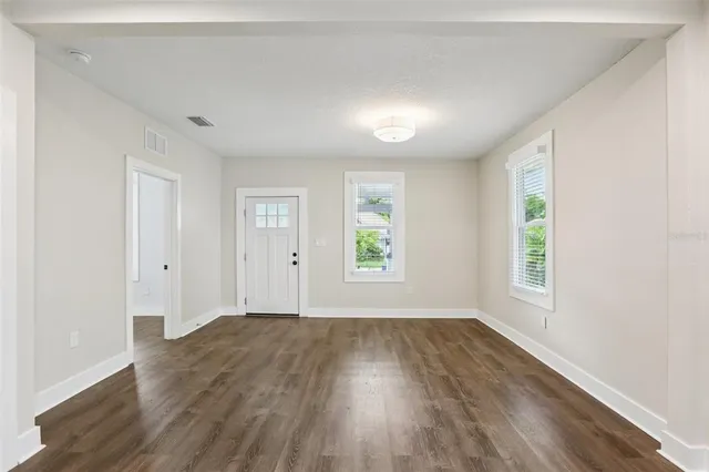 an empty room with wooden floor and windows