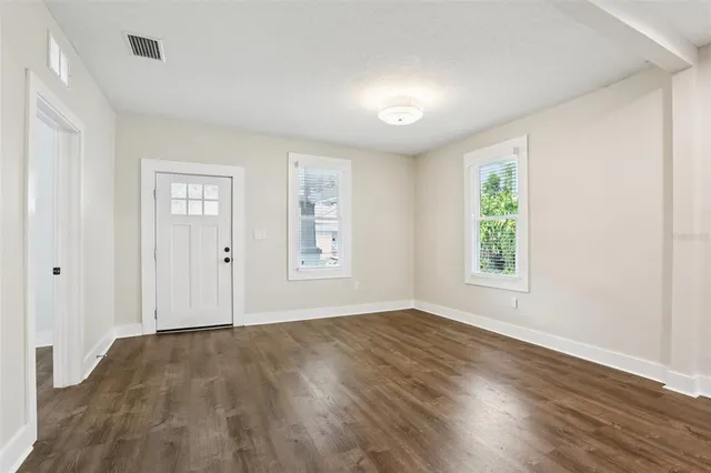 an empty room with wooden floor and windows