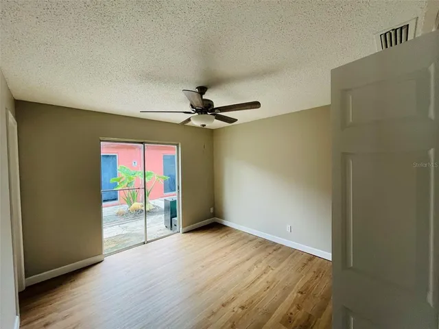 an empty room with wooden floor fan and windows