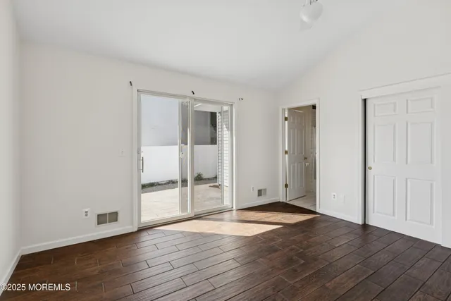 an empty room with wooden floor & windows