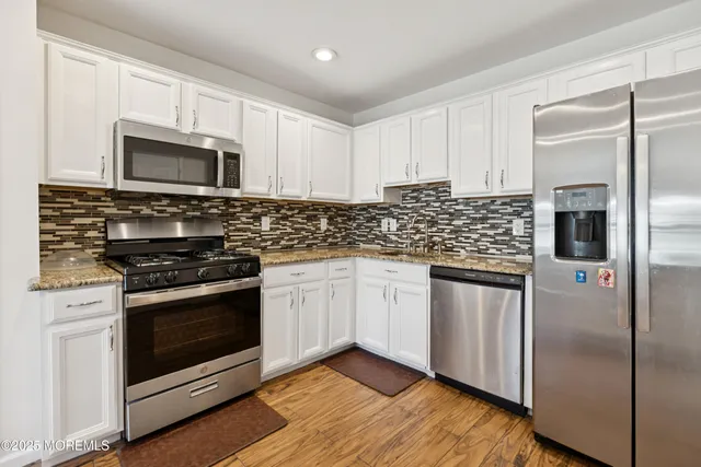a kitchen with stainless steel appliances granite countertop a stove a microwave and a refrigerator