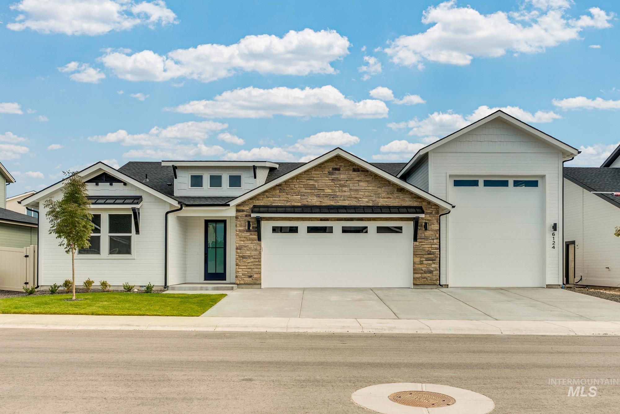 View of front of house with an attached garage, roof with shingles, driveway, stone siding, and a standing seam roof