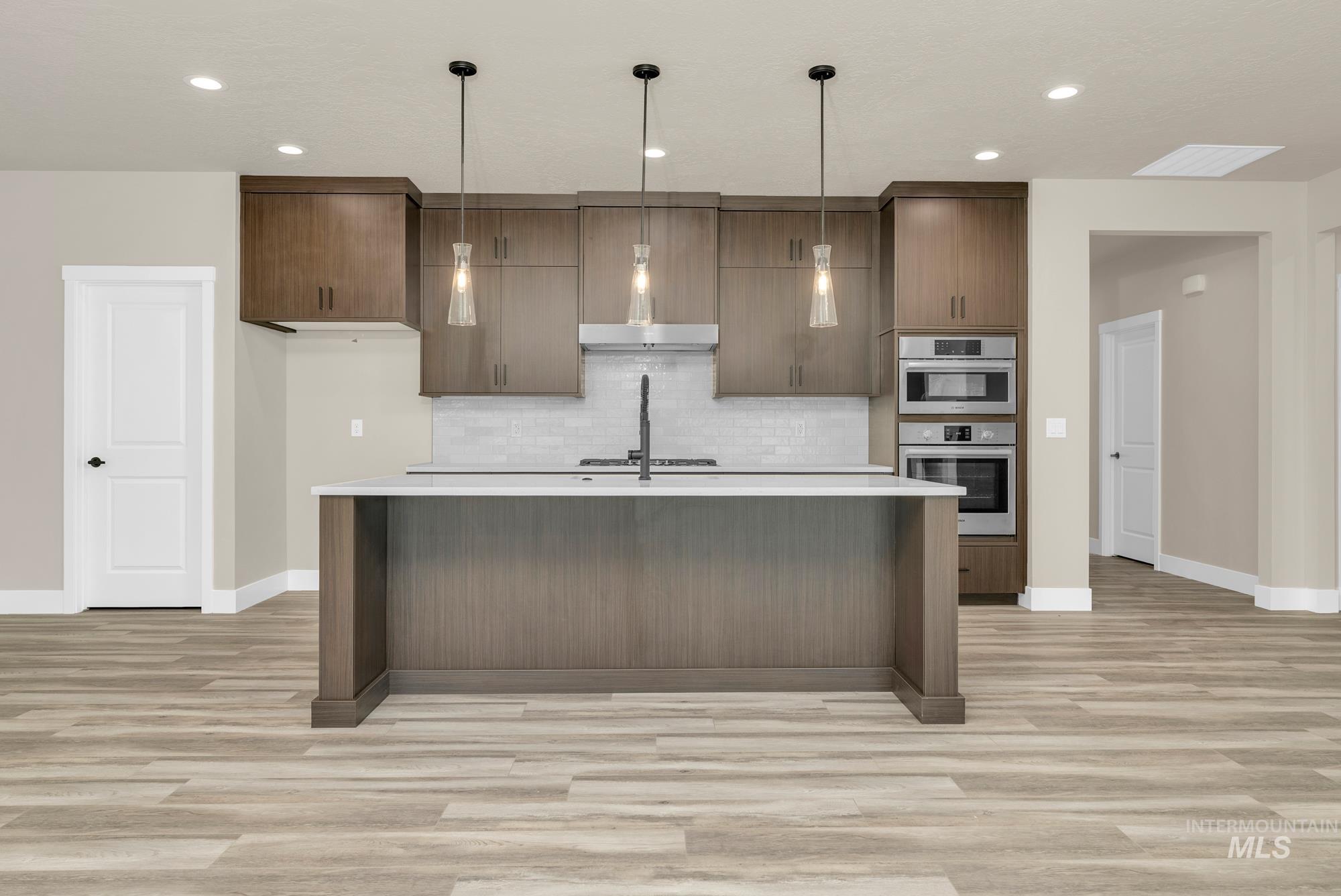 2772 West Jutland Street Meridian, ID 83642 - Photo 3 of 25 Kitchen with decorative light fixtures, light wood-type flooring, a kitchen island with sink, and modern cabinets