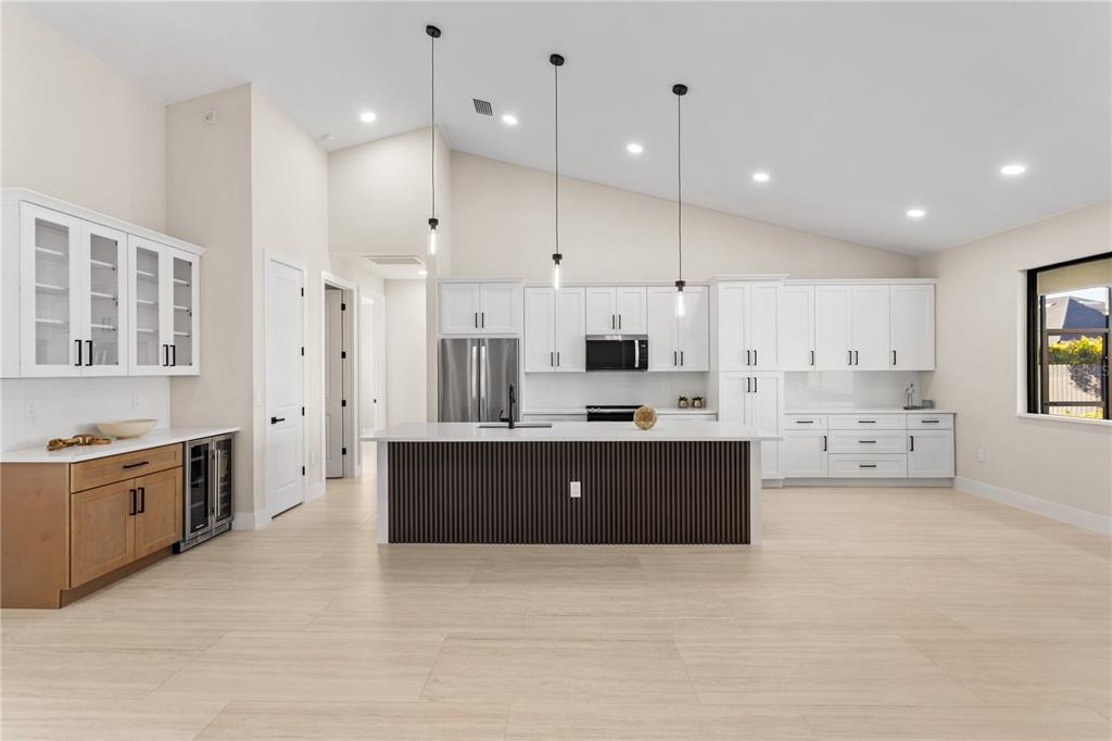 a large kitchen with stainless steel appliances kitchen island granite countertop a stove a sink a refrigerator and white cabinets