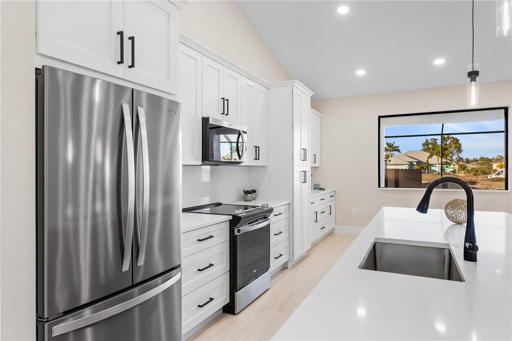 1711 Southwest 3rd Street Cape Coral, FL 33991 - Photo 11 of 45 a kitchen with stainless steel appliances a refrigerator sink and stove
