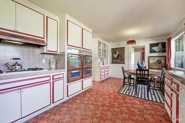 a kitchen with stainless steel appliances granite countertop a refrigerator a stove and a dining table with wooden floor