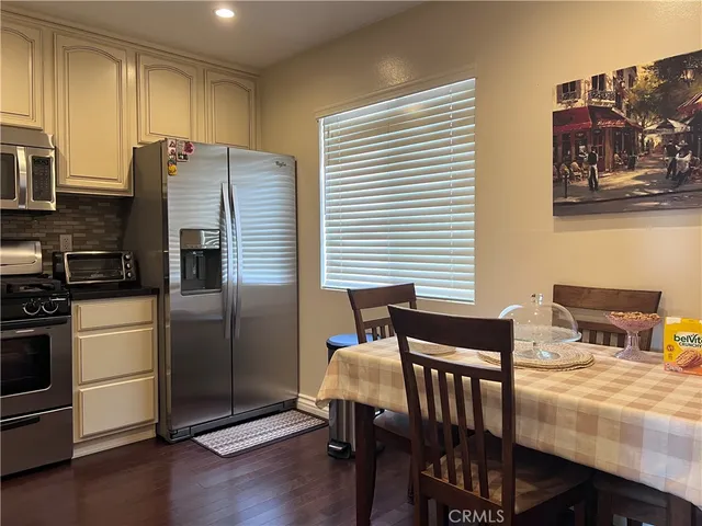 a kitchen with stainless steel appliances wooden floor dining table and chairs