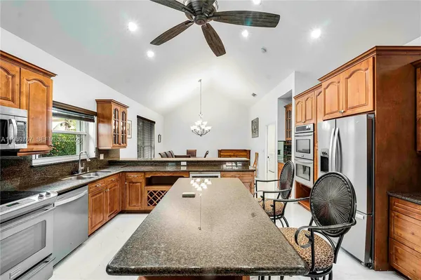 a kitchen with stainless steel appliances granite countertop a sink refrigerator and cabinets