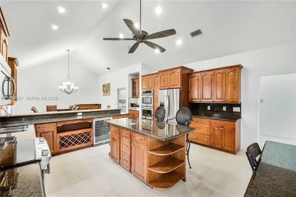 a kitchen with stainless steel appliances granite countertop a sink a stove and a wooden cabinets