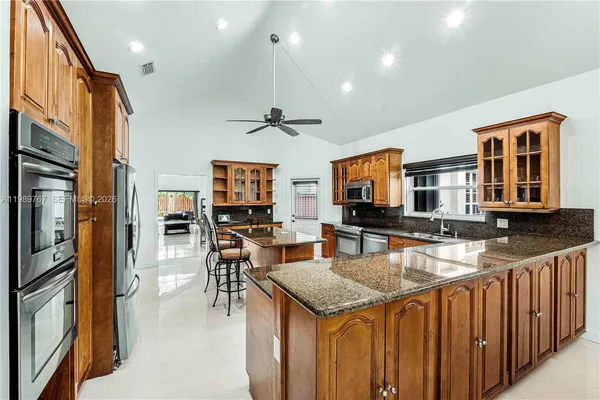 a kitchen with stainless steel appliances granite countertop a stove top oven a sink dishwasher a dining table and chairs with wooden floor