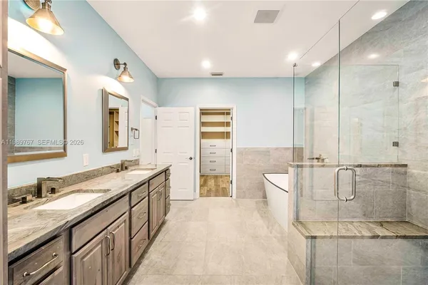a spacious bathroom with a double vanity sink a large mirror and a bathtub