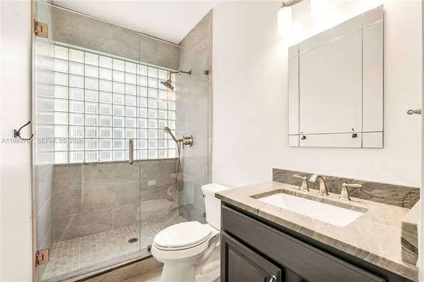 a bathroom with a granite countertop sink toilet and shower