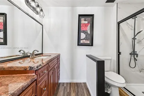 a bathroom with a granite countertop sink a toilet and a mirror