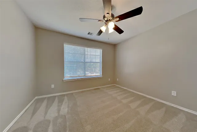 en empty room with windows and ceiling fan