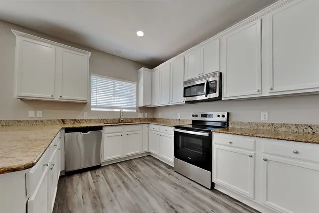 a kitchen with granite countertop cabinets stainless steel appliances and a sink