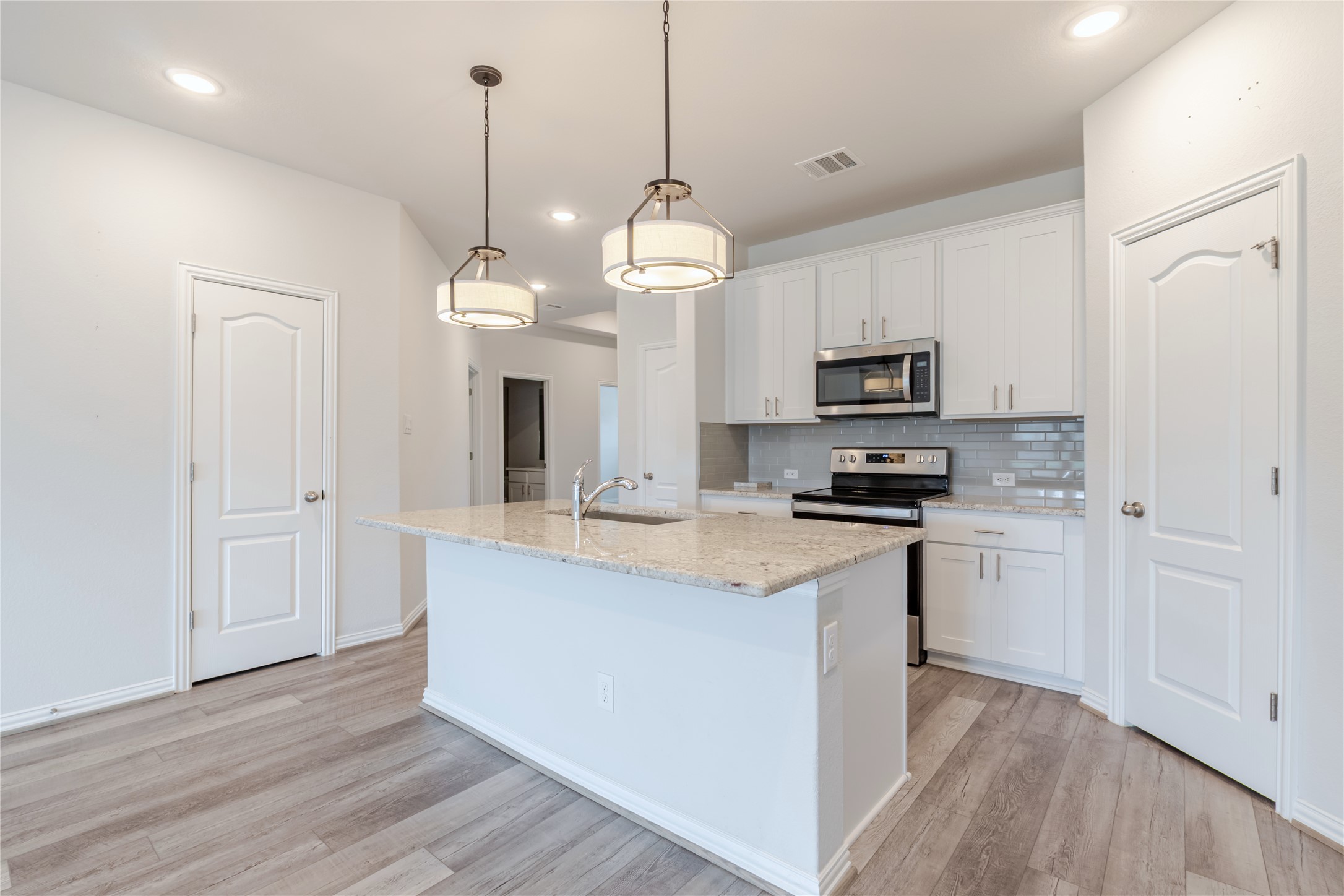 1117 Terrace View Georgetown, TX 78628 - Photo 16 of 25 Kitchen featuring a central island with an undermount sink, granite countertop, and pendant lighting