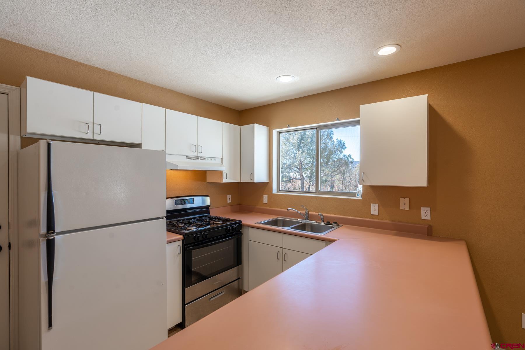 190 Pine Ridge Road Durango, CO 81301 - Photo 18 of 27 a kitchen with a refrigerator a stove a sink dishwasher and wooden cabinets with wooden floor