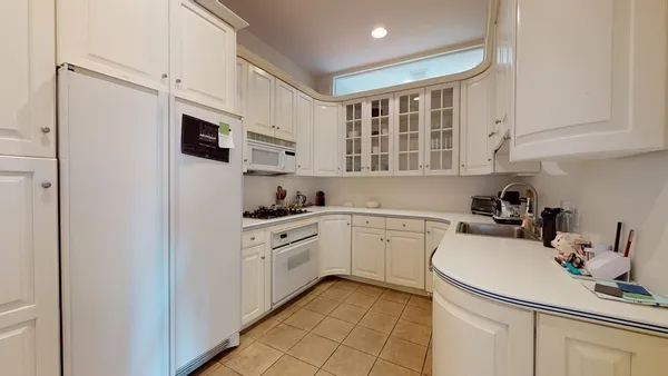a kitchen with a sink white cabinets and white appliances