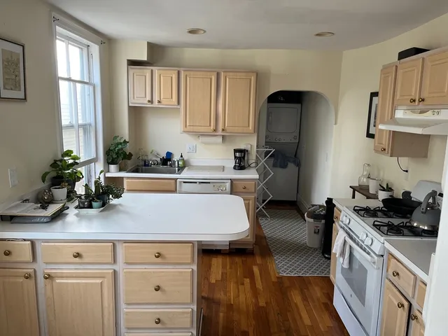 a kitchen with kitchen island a counter space a sink a stove and cabinets