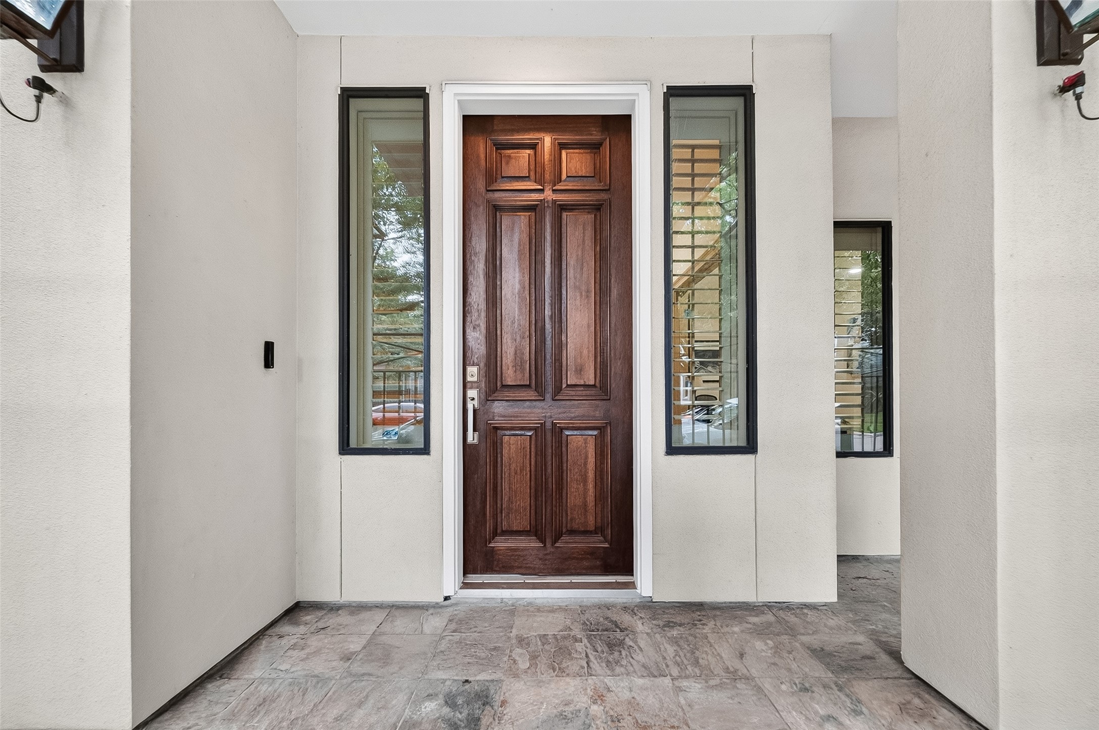2034 Colquitt Street, Unit A Houston, TX 77098 - Photo 4 of 41 This photo showcases a welcoming front entryway with a rich wooden door flanked by tall, narrow windows. The exterior is accented with neutral-toned walls and a stone-tiled porch, creating a stylish and inviting entrance.