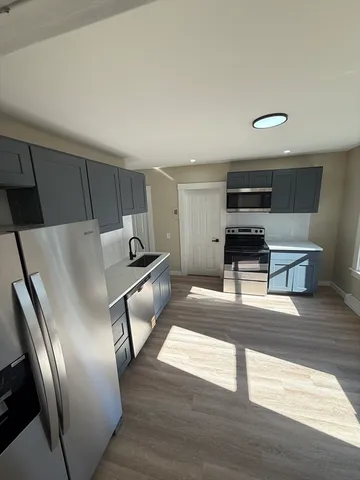 a living room with stainless steel appliances furniture a kitchen view and a refrigerator