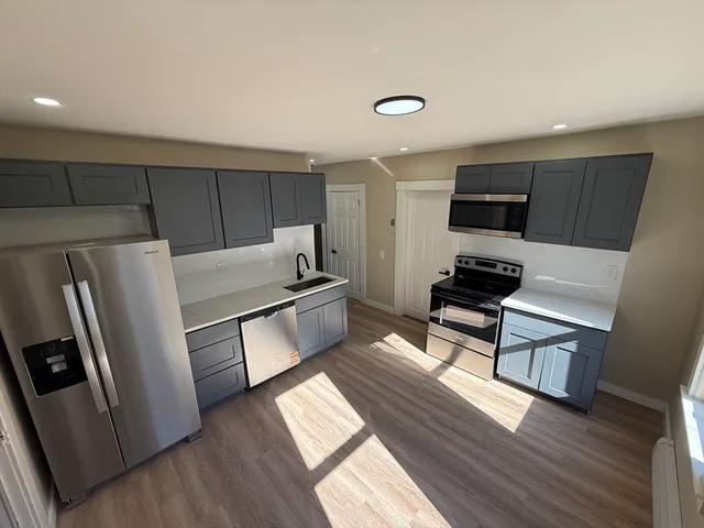 a kitchen with stainless steel appliances a refrigerator a stove top oven a sink and dishwasher a refrigerator with wooden floor