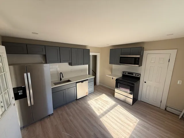 a kitchen with stainless steel appliances a refrigerator a stove a sink and a oven with wooden floor