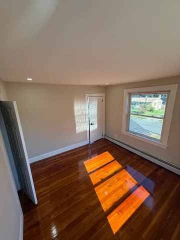a view of empty room with window and wooden floor