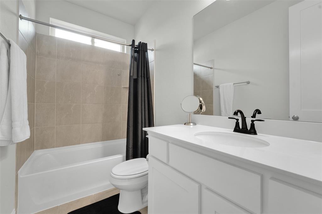 3520 Helios Lane Corinth, TX 76208 - Photo 23 of 37 Bathroom featuring a single vanity with an integrated sink, black hardware, a framed mirror, and white cabinetry