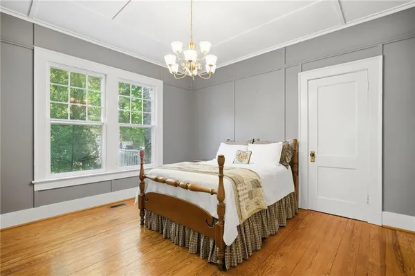 a bedroom with a bed a chandelier and a window