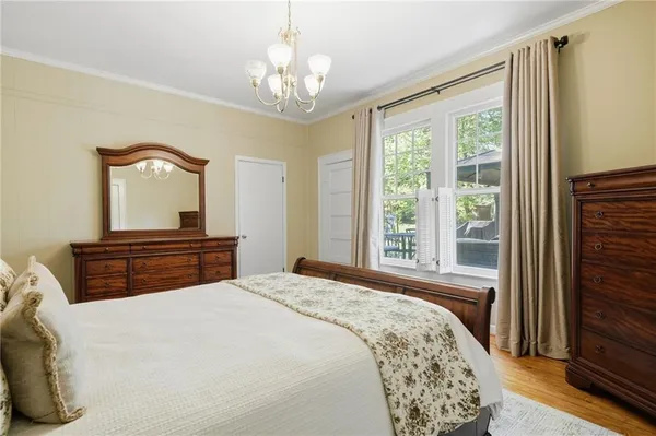 a bedroom with a large bed and a chandelier next to a window