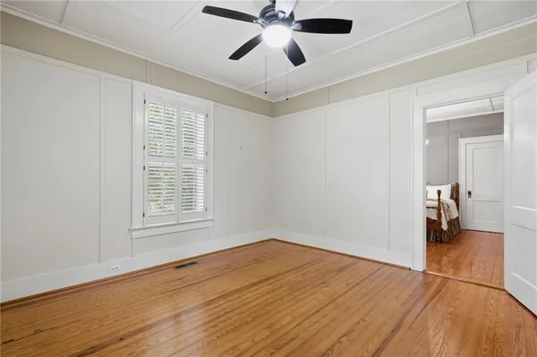 a view of empty room with wooden floor and fan