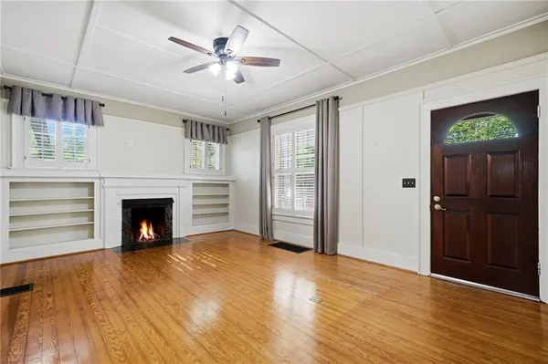 a view of a livingroom with a fireplace a ceiling fan and window
