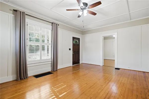a view of an empty room with a window and wooden floor