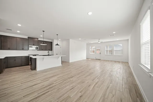 a large white kitchen with kitchen island a sink wooden floor and a large window