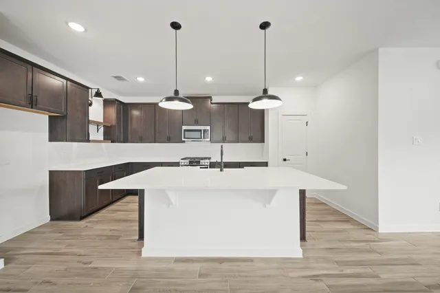 a view of a kitchen with kitchen island a sink stainless steel appliances and wooden floor