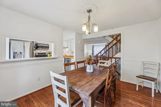 a dining room with wooden floor a chandelier a wooden table and chairs